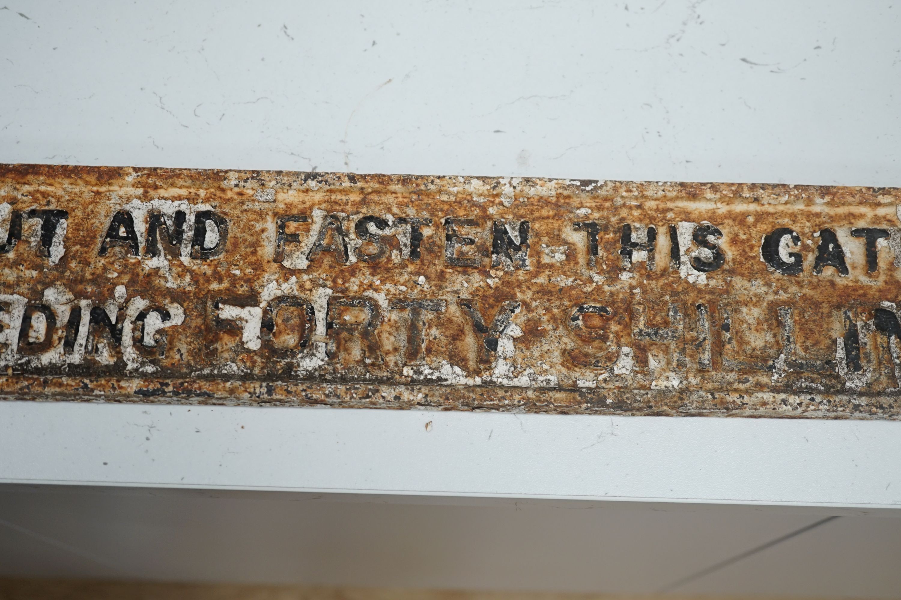 A cast iron gate sign, “any person who omits to shut and fasten this gate is liable to a penalty not exceeding forty shillings.”, 101 cms long.